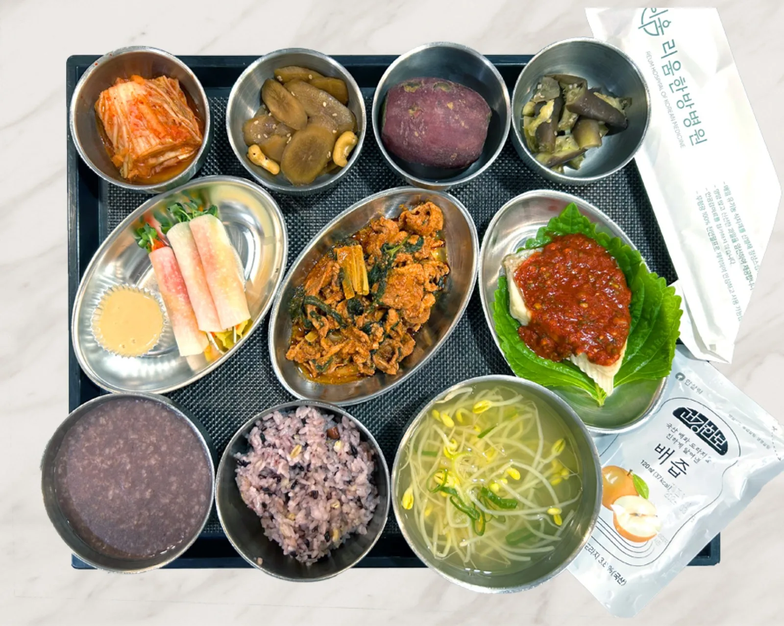 토마토소스를 올린 생선과 제육볶음에 콩나물국과 팥죽을 함께 낸 식판 · 리움한방병원 종로 식단